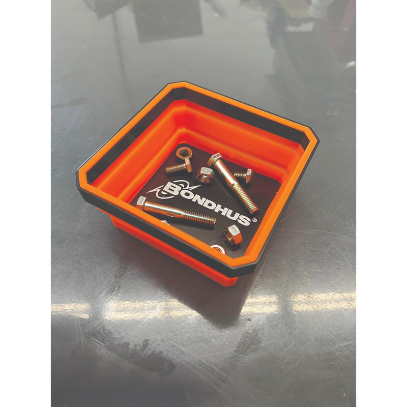 An orange and black BondHus silicone tray containing several small metal hardware components, photographed on a reflective gray surface.
